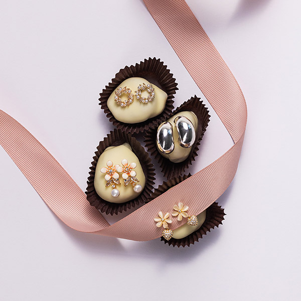 Pendientes de botón sobre pequeños bombones en moldes.