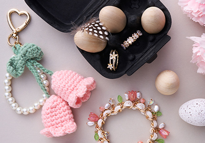 Pendientes, pulsera y llavero tejido entre decoración floral y accesorios de Pascua en tonos pastel.