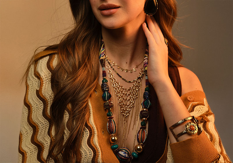 Una mujer lleva varios collares largos combinados en capas de forma elegante.