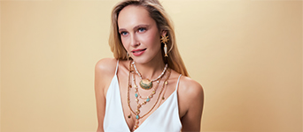 Mehrlagige Goldketten mit pastellfarbenen Details setzen einen eleganten Akzent.