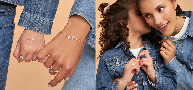 Twee personen dragen fijne gouden sieraden met hartmotief: armbanden en ringen aan de handen, evenals kettingen en oorbellen gecombineerd met spijkerjacks tegen een warme, neutrale achtergrond.