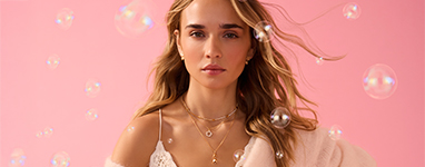 Een vrouw kijkt recht in de camera en laat een ketting zien.