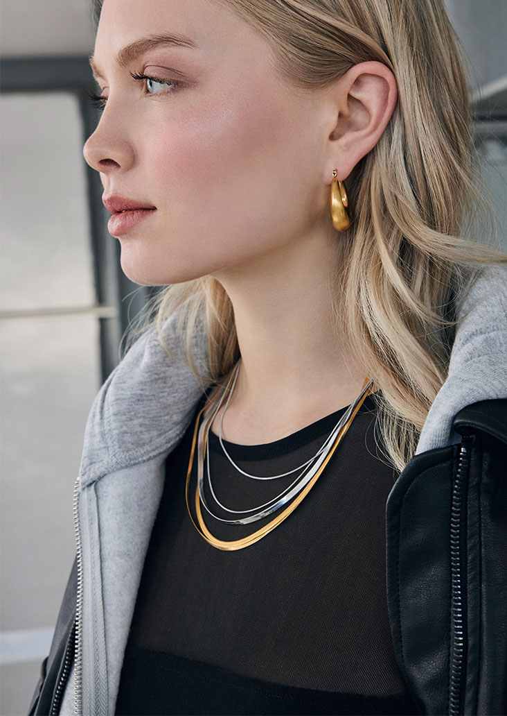 goldene hängeohrringe, ohrschmuck, ketten, gestapelte ketten, schwarzes oberteil