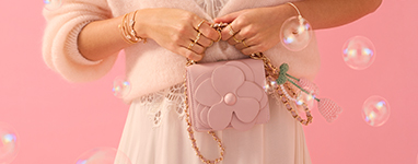 Kobieta trzyma przed kamerą różową torebkę.