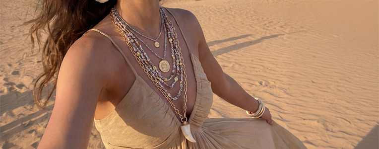 Collares en capas se presentan con estilo en una persona con un atuendo ligero en un cálido paisaje desértico.