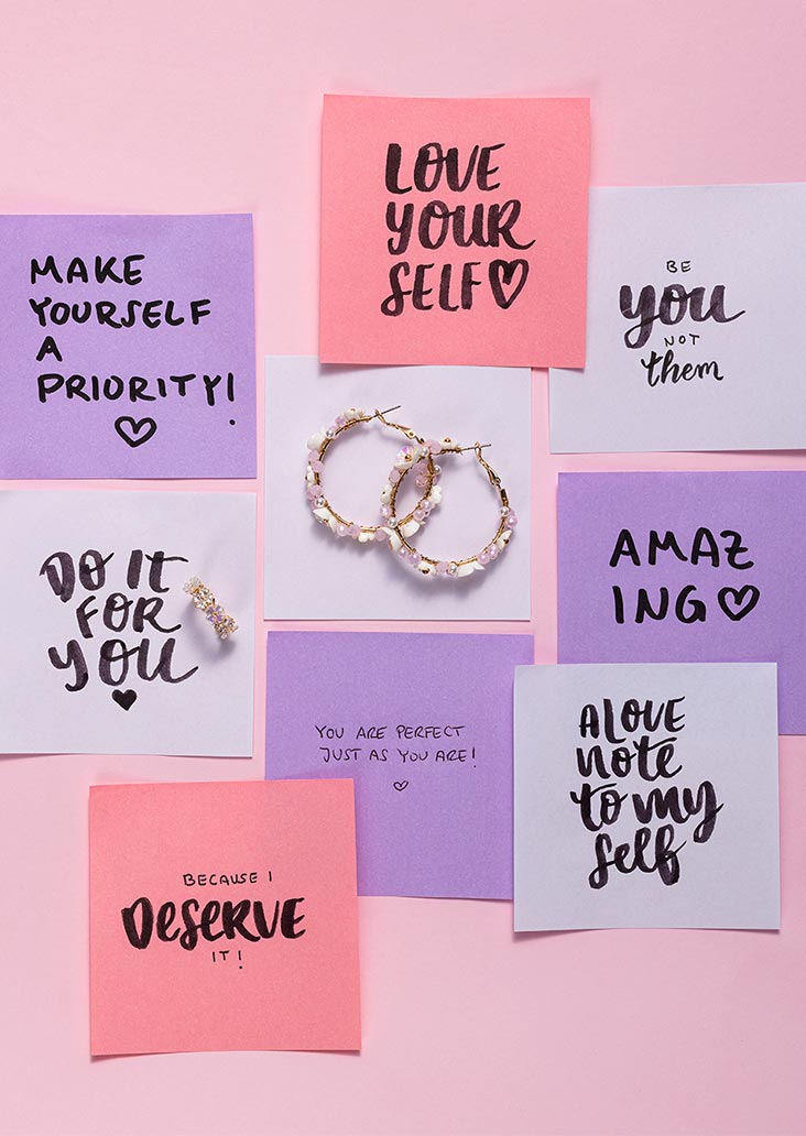 Een verzameling handgeschreven briefjes in blauw, roze en paars, met in het midden twee ringen.