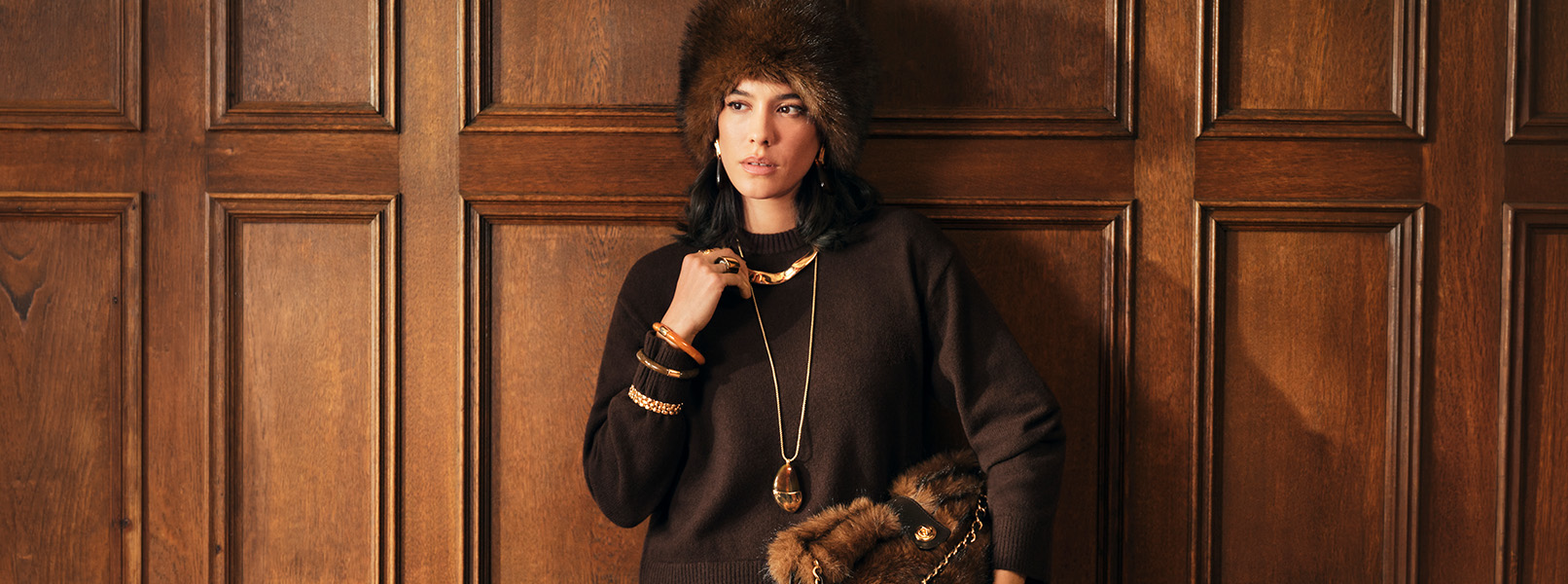 Pelzmütze, Dunkler Pullover, Goldschmuck, Lange Halskette, Fellhandtasche