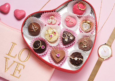 Une boîte en forme de cœur contenant des chocolats en forme de cœur à côté d'une montre.