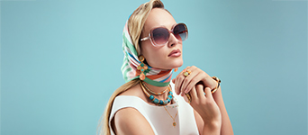 Goldene Ringe, Armbänder und türkisfarbene Ketten verleihen dem Look einen eleganten Retro‑Riviera‑Akzent.